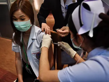 Seorang petugas kesehatan menerima vaksin Covid-19 CoronaVac dari Sinovac, di Institut Penyakit Menular Bamrasnaradura di Bangkok, Minggu (28/2/2021). Meski tertinggal diantara negara-negara Asia Tenggara lainnya, akhirnya Thailand memulai kampanye vaksin COVID-19. (Lillian SUWANRUMPHA/AFP)