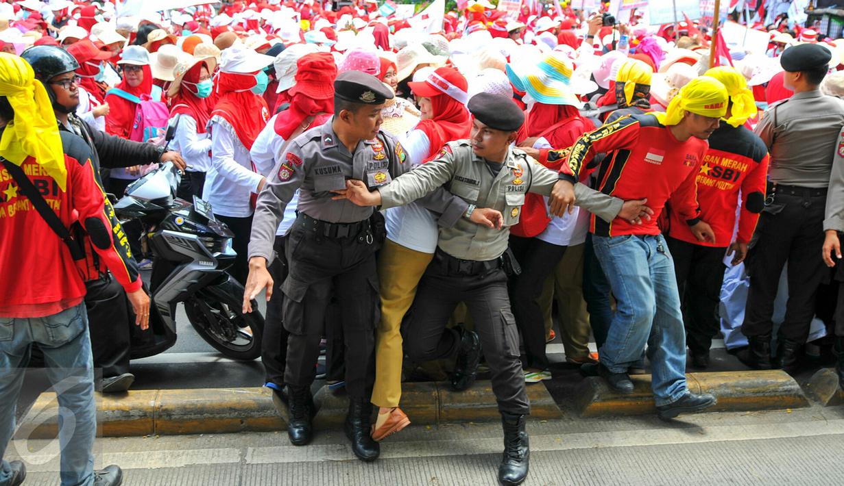 Personel kepolisian berusaha menahan para bidan desa yang berupaya menutup akses jalan saat demonstrasi di depan gedung Kemenkes, Jakarta, Rabu (4/5). Para bidan menuntut diangkat menjadi pegawai tetap tanpa syarat.  (Liputan6.com/Yoppy Renato)