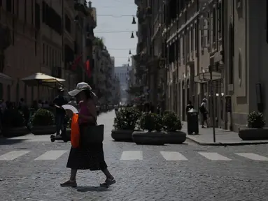 Seorang wanita melambaikan kipasnya saat berjalan di pusat kota Roma, Selasa, 22 Agustus 2023. (AP Photo/Gregorio Borgia)