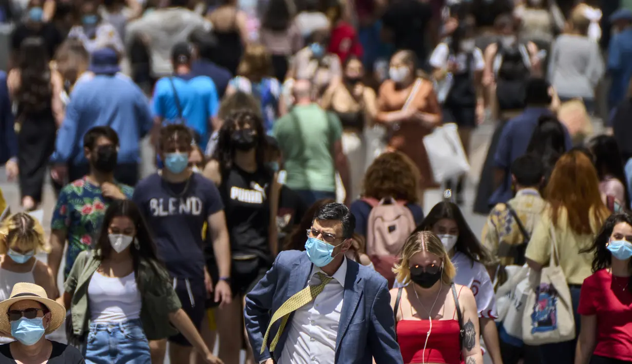 Orang-orang yang memakai masker berjalan di sepanjang jalan di Madrid, Spanyol, Kamis (24/6/2021). Spanyol melonggarkan aturan pandemi COVID-19, mengizinkan orang berhenti mengenakan masker di luar ruangan dan mengizinkan penggemar olahraga kembali ke dalam stadion.  (AP Photo/Manu Fernandez)