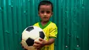 Seorang anak Rohingya mengenakan jersey timnas Brasil sambil memegang bola di kamp pengungsi Kutupalong di Ukhia, Bangladesh, 19 Juli 2018. Bagi pengungsi anak-anak Rohingya, Piala Dunia 2018 ini adalah ajang pertama bagi mereka. (AFP/Munir UZ ZAMAN)