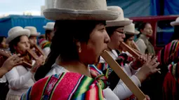 Pemain musik wanita bermain seruling saat prosesi arak-arakan patung dewa Ekeko di La Paz, Bolivia (23/1). Alasita ini awalanya sebuah pameran dimana orang pribumi bertukar miniatur dan beberapa barang kebutuhan penting lainnya. (AP Photo / Juan Karita)