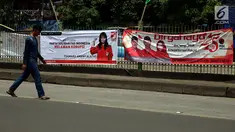 Pejalan kaki berjalan di depan spanduk partai politik yang terpampang di Jalan Sultan Agung, Manggarai, Jakarta, Selasa (16/1). Memasuki 2018, parpol berlomba mengambil hati rakyat dengan berbagai janji terpampang di spanduknya. (Liputan6.com/JohanTallo)