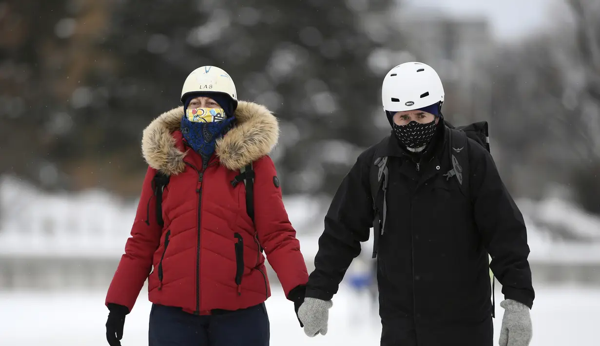 Orang-orang memakai masker berjalan di sepanjang Rideau Canal Skateway pada hari pembukaannya di tengah pandemi COVID-19 di Ottawa, Ontario, Kamis (28/1/2021). Rideau Canal Skateway dibuka Kamis pagi dengan sejumlah tindakan pencegahan COVID-19. (Justin Tang/The Canadian Press via AP)