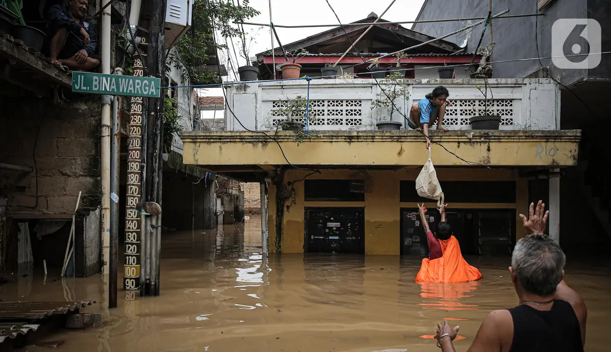 Warga menurunkan barang saat banjir di kawasan Rawajati, Kalibata, Jakarta, Senin (10/10/2022). Tingginya curah hujan di kawasan Bogor mengakibatkan ratusan rumah di enam RT Kelurahan Rawajati terendam banjir dengan ketinggian mencapai dua meter. (Liputan6.com/Faizal Fanani)