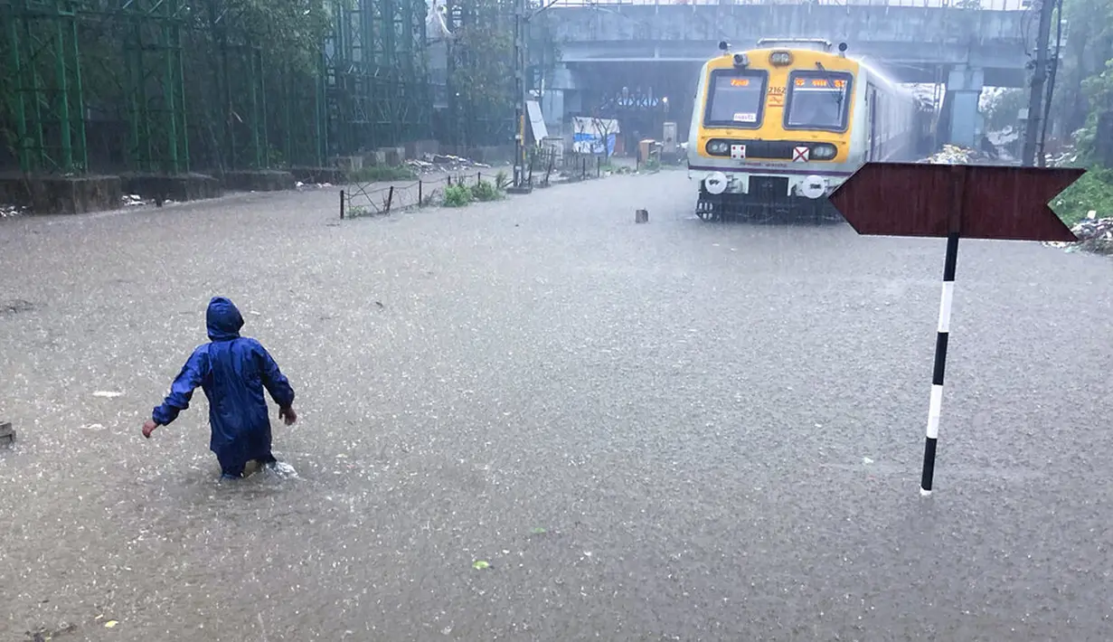 Seorang pria berjalan melintasi rel kereta api yang terendam banjir saat hujan lebat di Mumbai, India, Rabu (9/6/2021). Mumbai terendam banjir usai diguyur hujan lebat. (AP Photo/Rafiq Maqbool)