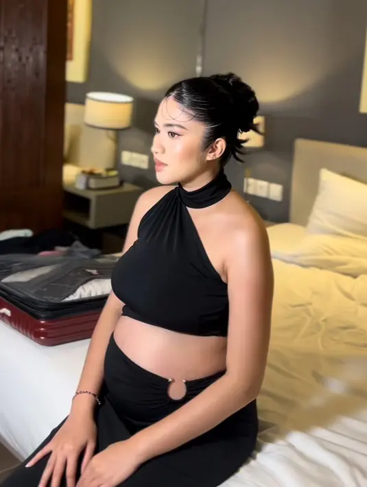 Ochi Rosdiana tampil dengan dress halter neck hitam one shoulder dengan cut out di bagian perut yang memerlihatkan baby bumpnya. [@muabyangelc]