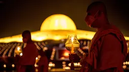 Biksu Buddha memegang lilin selama perayaan Makha Bucha di tengah pandemi COVID-19, di Wat Dhammakaya, utara Bangkok, Jumat (26/2/2021). Upacara keagamaan ini pun menjadi salah satu yang terbesar di Thailand karena banyaknya umat Buddha yang tinggal di wilayah Gajah Putih. (Jack TAYLOR/AFP)
