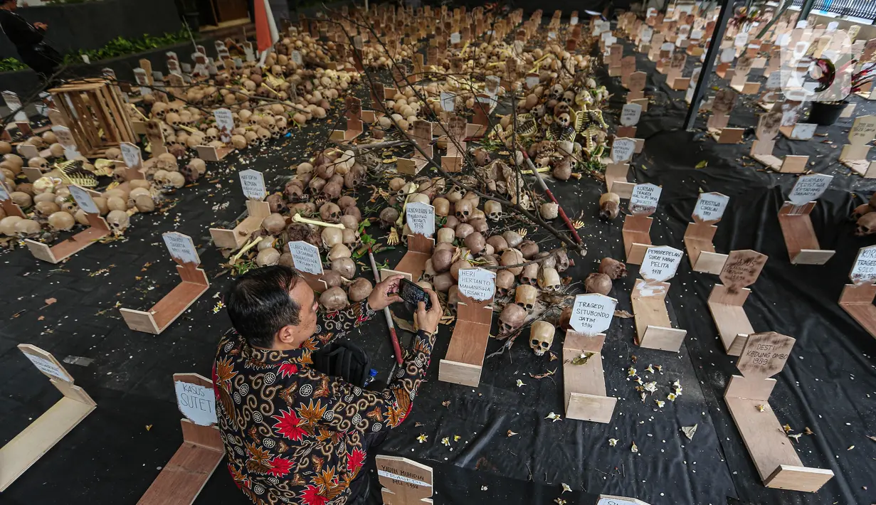 Pengunjung melihat 2.000 tengkorak dan 1.000 kuburan yang ditampilkan saat aksi instalasi peringatan 26 tahun Reformasi dan napak tilas pelanggaran HAM Orde Baru di Jalan Diponegoro, Jakarta, Selasa (21/5/2024). (Liputan6.com/Angga Yuniar)