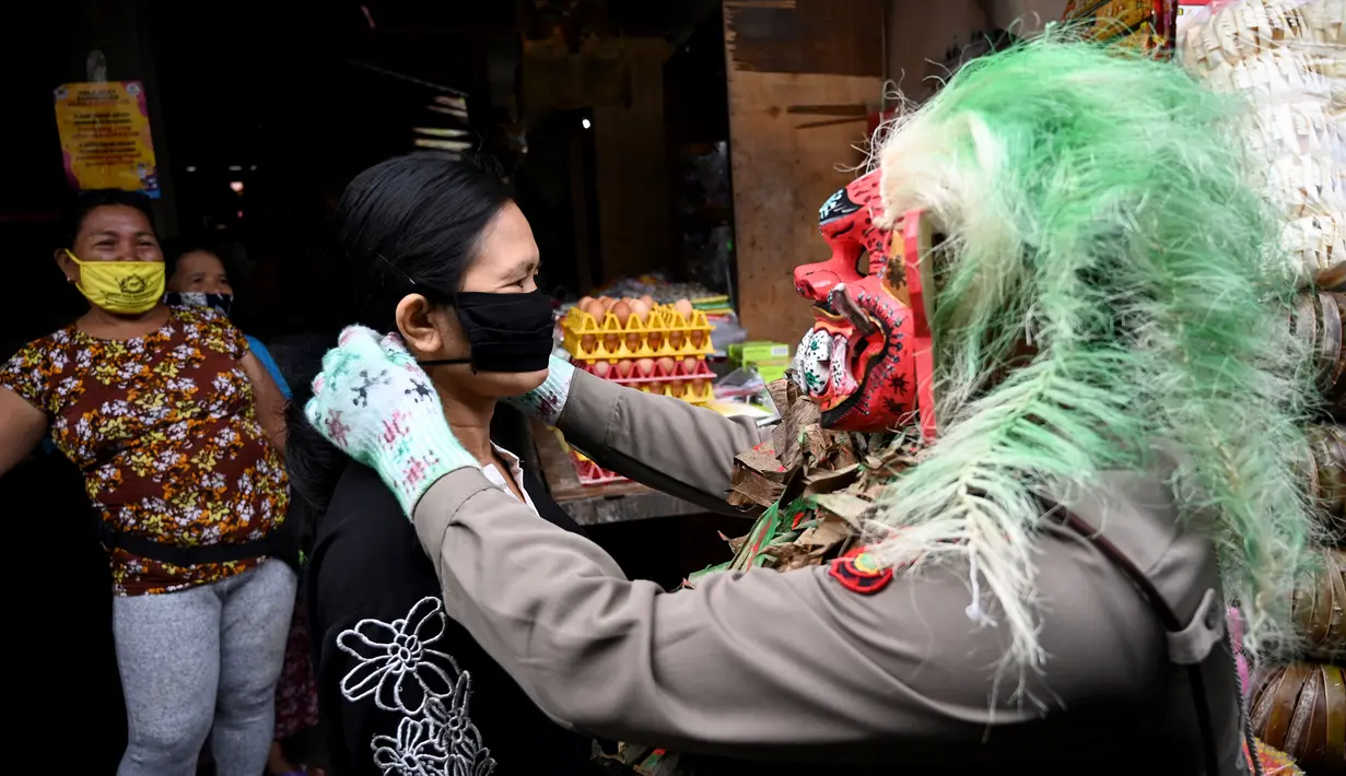 Polisi mengenakan topeng menyeramkan yang disebut "Leak" saat sosialisasi encegahan COVID-19 di pasar tradisional di Kerobokan, Denpasar, Kamis (14/5/2020). Kegiatan itu mengimbau masyarakat agar selalu mengenakan masker, rutin mencuci tangan, menjaga jarak, serta tidak mudik. (SONNY TUMBELAKA/AFP)