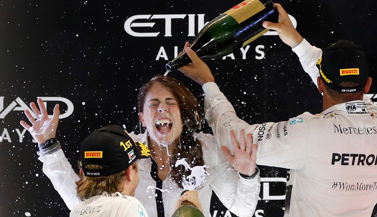 Nico Rosberg dan Lewis Hamilton mengguyur Kim Stevens, salah satu staf tim Mercedes GP di podium juara F1 GP Abu Dhabi di Sirkuit Yas Marina, Abu Dhabi, UEA, Minggu (29/11/2015). (EPA/Ali Haider)