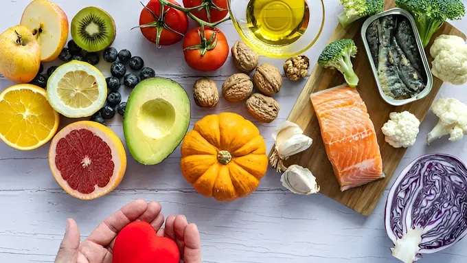 Sebuah tangan memegang benda berbentuk hati dengan bahan makanan di sekitarnya (Foto Dok: Freepik/corazzaphotos)