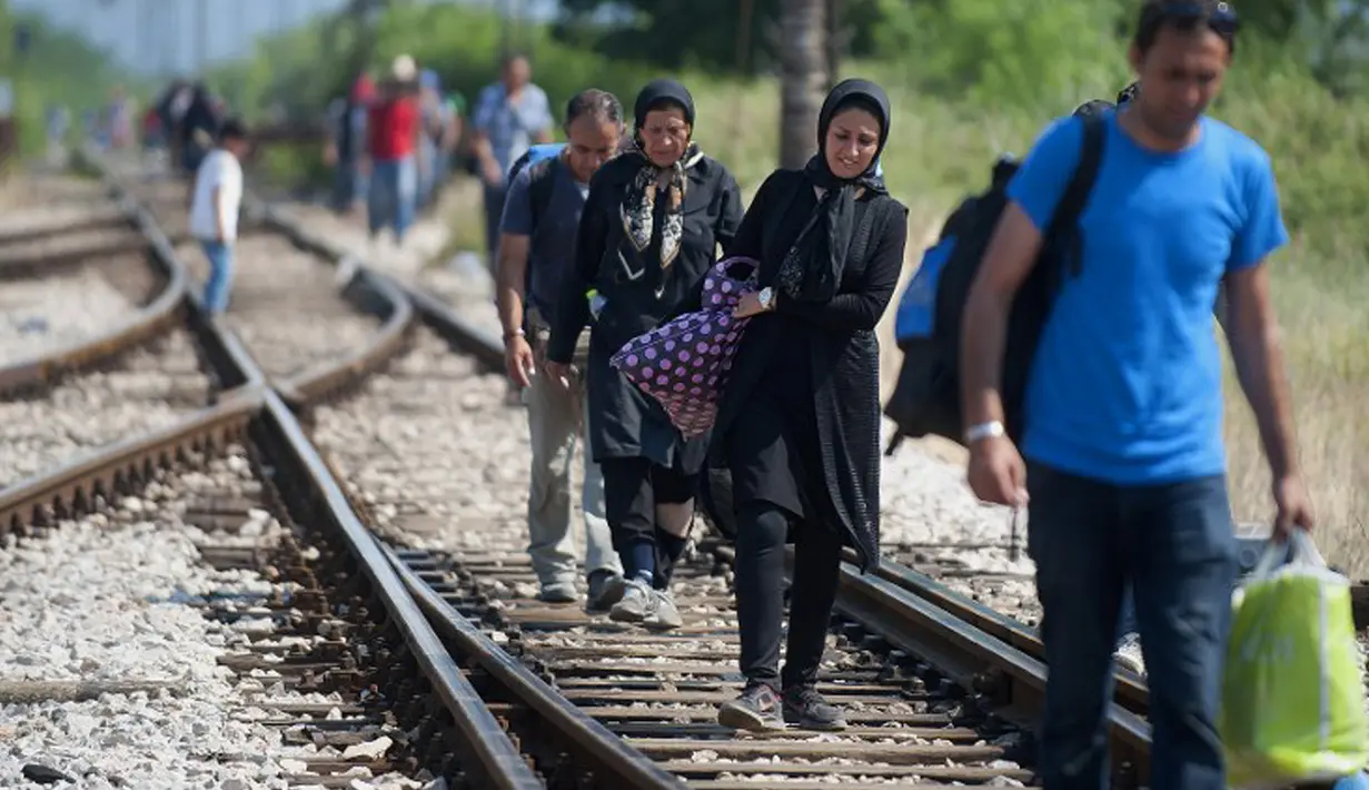 Imigran dengan membawa barang menyusuri rel kereta api saat perjalanan menuju Gevgelija, wilayah perbatasan Macedonia-Yunani, Kamis (9/7/2015). Mereka menempuh ribuan kilometer agar dapat mengejar kereta api tujuan Serbia. (AFP PHOTO/Robert ATANASOVSKI)