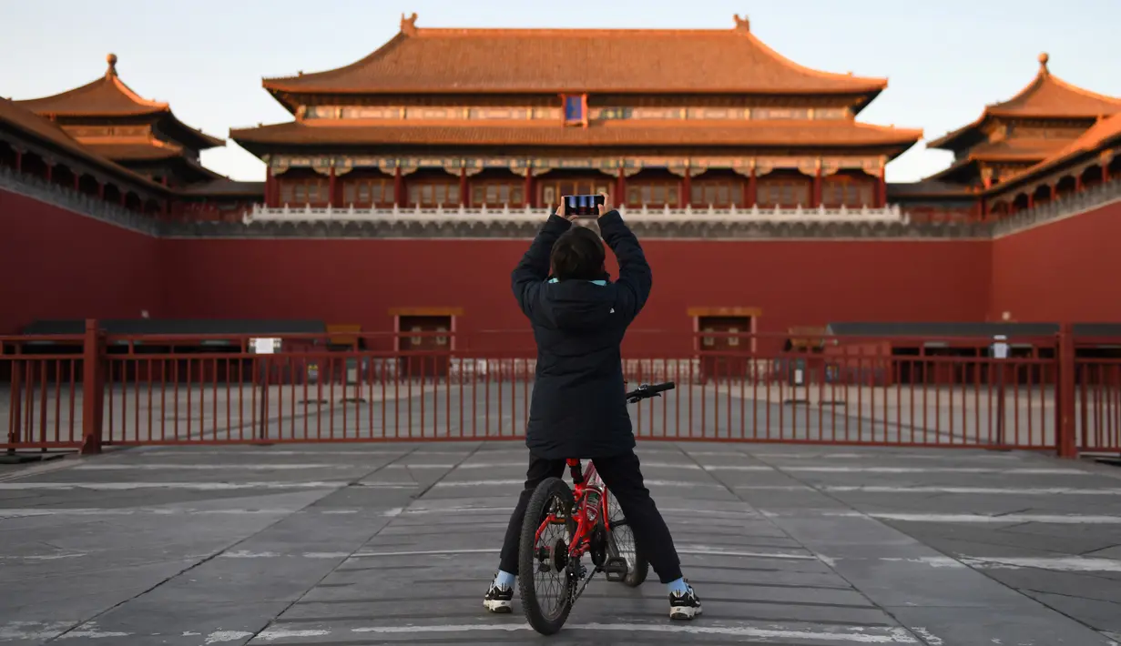 Seorang anak laki-laki mengambil foto di luar Kota Terlarang yang ditutup di Beijing pada Selasa (4/2/2020). Mencegah korban virus corona bertambah, China menutup  banyak destinasi wisata termasuk Kota Terlarang yang ditutup untuk kunjungan wisatawan sejak 24 Januari 2020 lalu. (GREG BAKER/AFP)