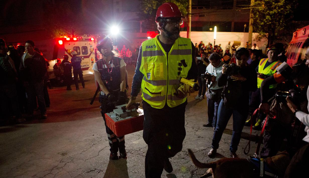 Tim penyelamat membawa peralatan menuju ke garasi parkir bawah tanah yang runtuh di sebuah kompleks di Mexico City (10/4). Petugas juga menggunakan anjing pelacak untuk mencari korban. (AP Photo/Rebecca Blackwell)