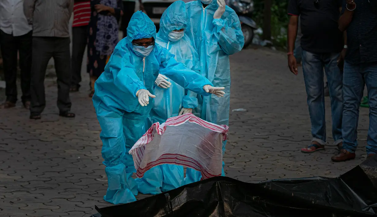 Seorang anak laki-laki berusia 9 tahun (tengah) bersama ibunya (kiri) dengan alat pelindung diri melakukan ritual saat kremasi ayahnya yang meninggal karena virus corona COVID-19 di Gauhati, India pada 28 September 2020. (AP Photo/Anupam Nath)