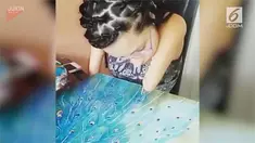 Seorang wanita yang juga penyandang disabilitas melukis burung merak tanpa bantuan orang lain.