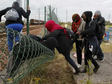 Sejumlah imigran gelap berusaha melewati pagar keamanan terminal Eurotunnel di Coquelles dekat Calais di Prancis, 29 Juli 2015. Ribuan imigran tersebut mencoba memasuki Terowongan Channel menuju Inggris melalui Prancis. (REUTERS/Pascal Rossignol)