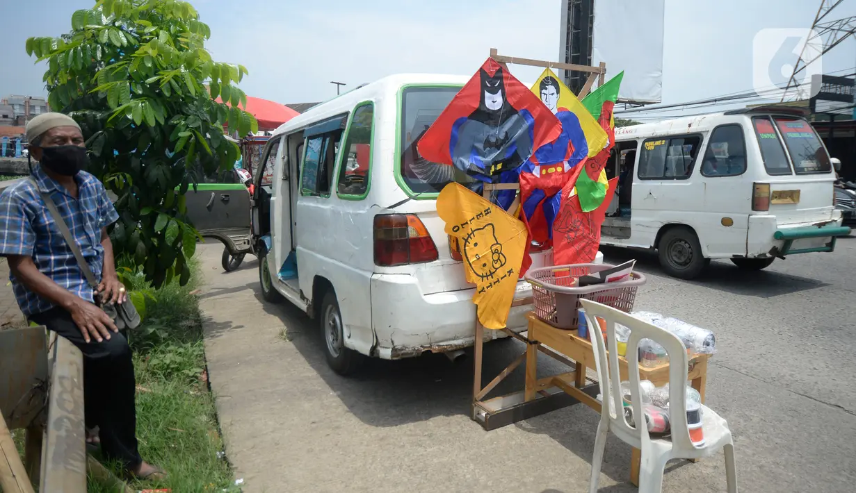 Abdul Karim (65) sopir angkotan Jurusan Ciputat-Muncul menunggu pembeli saat menjual layangan hias di Pingir Jalan Siliwangi, Tangerang Selatan, Banten, Senin (29/9/2020). Abdul Karim beralih profesi menjual layangan hias akibat penumpang sepi untuk memenuhi kebutuhan dapur.  (merdeka.com/Dwi Narwok