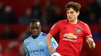 Bek Manchester City, Benjamin Mendy (kiri) berusaha merebut bola yang dibawa gelandang Manchester United, Daniel James pada pertandingan leg pertama semifinal Piala Liga Inggris di Old Trafford (7/1/2020). City menang 3-1 atas MU. (AFP/Paul Ellis)