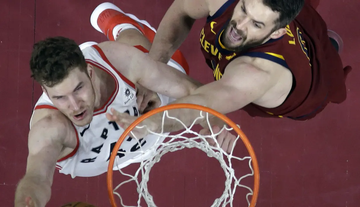 Pemain Toronto Raptors, Jakob Poeltl (kiri) melakukan layup saat diadang pemain Cleveland Cavaliers, Kevin Love pada lanjutan NBA basketball game di Quicken Loans Arena, (21/3/2018) Cleveland. Cavs menang 132-129. (AP/Tony Dejak)