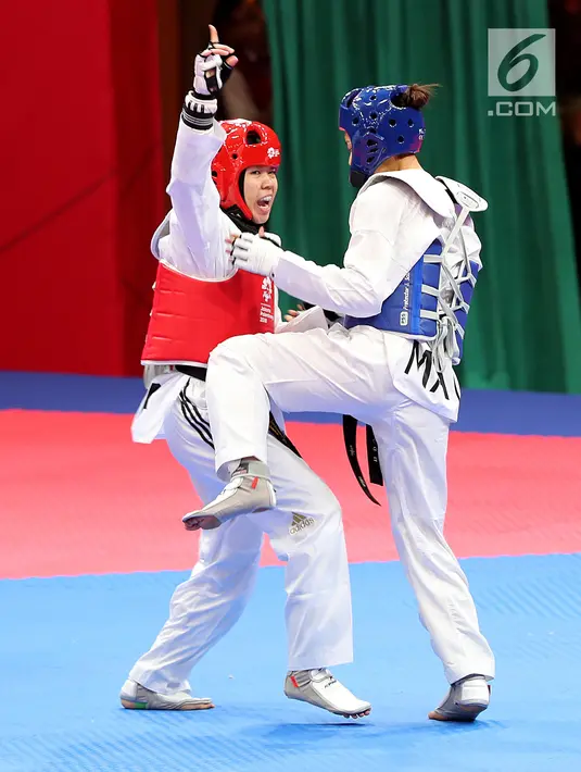 Atlet taekwondo putri Indonesia, Fitriyana Yusuf berhadapan dengan Liu Qing dari Makau pada babak 16 besar di Jakarta Convention Center (JCC), Senin (20/8). Fitriyana kalah tipis 21 - 25 pada kelas Wanita 67 kg. (Liputan6.com/Fery Pradolo)