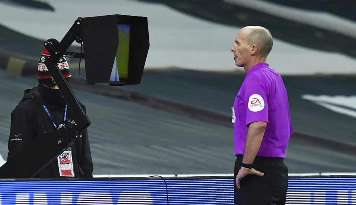 Wasit Mike Dean menyaksikan insiden pada layar VAR sebelum memberikan kartu merah kepada pemain Brentford Pelenda Joshua Dasilva saat melawan Tottenham Hotspur pada pertandingan semifinal Piala Liga Inggris di Tottenham Hotspur Stadium, London, Inggris, Selasa (5/1/2021). (Glyn Kirk/Pool via AP)