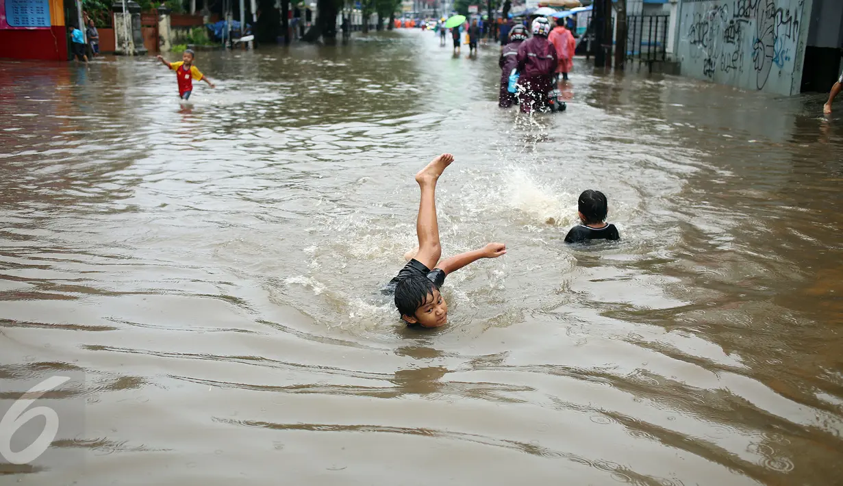Seorang anak asyik bermain banjir yang merendam kawasan Benhil RT 03 RW 05, Jakarta Pusat, Selasa (21/1). Hujan deras yang mengguyur sejak Selasa dinihari mengakibatkan kawasan tersebut mengalami banjir. (Liputan6.com/Johan Tallo)
