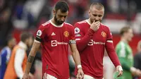 Pemain Manchester United atau MU Bruno Fernandes dan Luke Shaw berjalan keluar lapangan usai menghadapi Everton pada laga Liga Inggris di Old Trafford, Sabtu, 2 Oktober 2021. Laga berakhir imbang 1-1. (AP Photo/Dave Thompson)