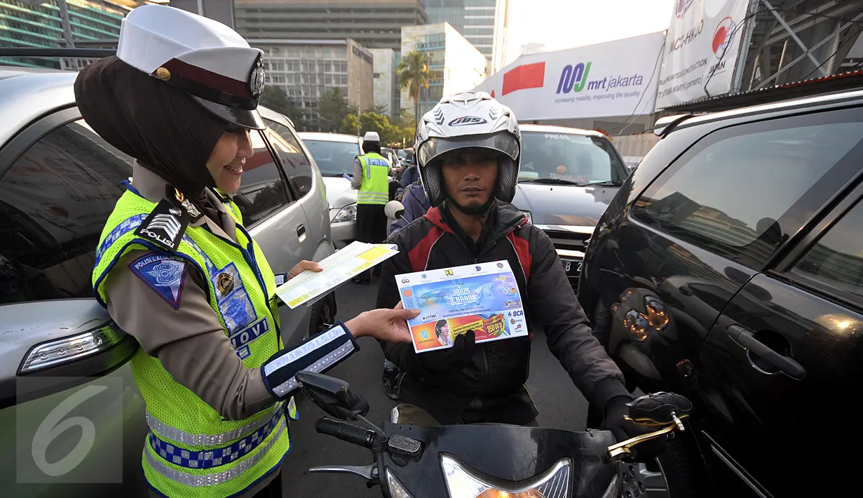 Polisi wanita dari Polda Metro Jaya membagikan peta mudik 2015 kepada pengendara di kawasan Bundaran HI, Jakarta, Jumat (26/6/2015). Pembagian peta tersebut diharapkan mampu meningkatkan keselamatan dalam bermudik. (Liputan6.com/Johan Tallo)