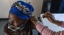 Seorang wanita divaksinasi COVID-19 di Rumah Sakit Lenasia South, dekat Johannesburg, Rabu (1/12/2021). Dokter Afrika Selatan mengatakan peningkatan pesat dalam kasus COVID-19 yang dikaitkan dengan varian baru omicron tampaknya hanya menyebabkan gejala ringan. (AP Photo/ Shiraaz Mohamed)
