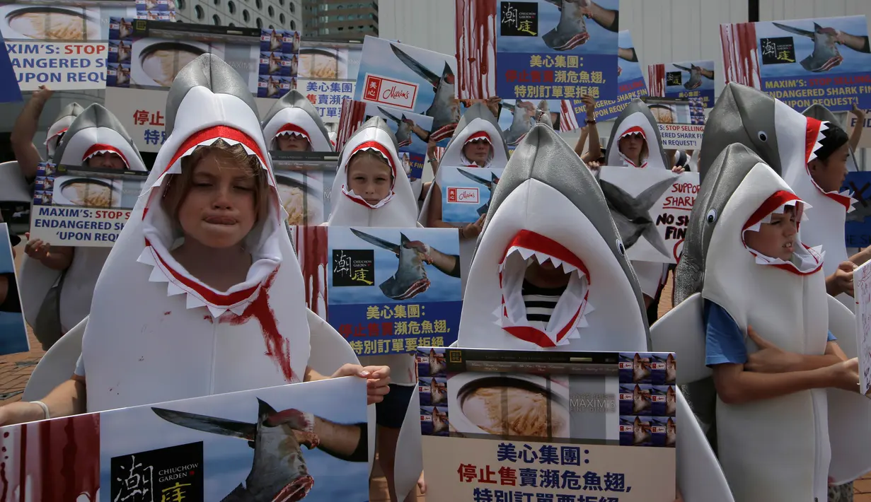 Aktivis konservasi hewan mengenakan pakaian hiu dan membawa poster saat menggelar aksinya di dekat restoran di Hong Kong (10/6). Para aktivis memprotes penjualan sup sirip ikan hiu yang masih banyak di Hong Kong. (AP Photo / Kin Cheung)