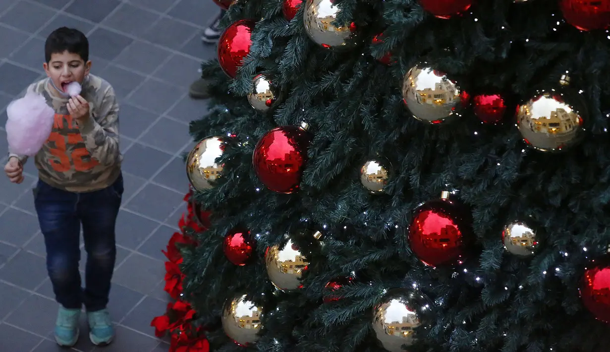 Seorang anak berjalan di dekat pohon Natal di pusat kota Beirut, Lebanon, pada 13 Desember 2020. Baru-baru ini, berbagai dekorasi Natal telah dipasang di pusat kota Beirut menyambut liburan Natal dan Tahun Baru mendatang meski sedang dilanda pandemi COVID-19 dan krisis ekonomi. (Xinhua/Bilal Jawich)