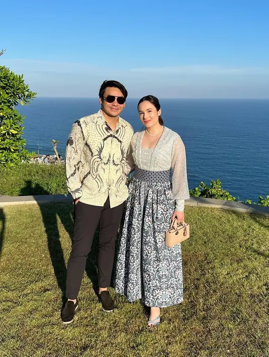 Dalam undangan pernikahan lain, Chelsea Islan tampil anggun dengan atasan semi-kebaya dengan bawahan rok lebar batik warna silver. Sementara itu, Rob juga tampil gagah memakai batik. Keduanya tampil begitu serasi dengan potret latar belakang keindahan laut. (Liputan6.com/IG/@robclintonkardinal)