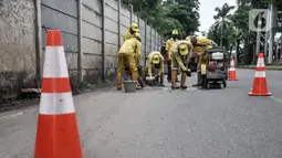 Pekerja Suku Dinas Bina Marga Jakarta Utara menyelesaikan perbaikan jalan jelang gelaran balap liar legal di Jalan Inspeksi Kali Ancol, Pademangan, Rabu (12/1/2022). Polda Metro Jaya resmi menjadikan Jalan Inspeksi Kali Ancol sebagai arena balap liar legal. (merdeka.com/Iqbal S. Nugroho)