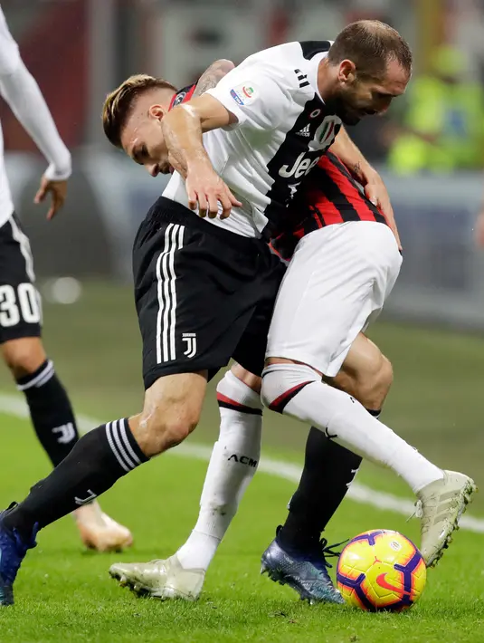 Gelandang AC Milan, Samu Castillejo berebut bola dengan bek Juventus, Giorgio Chiellini saat bertanding pada lanjutan Liga Serie A Italia di stadion San Siro, Milan (11/11). Juventus menang 2-0 atas AC Milan. (AP Photo / Luca Bruno)