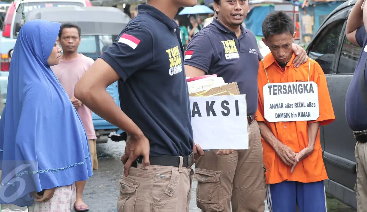 Petugas merangkul Anwar alias Rizal, tersangka  pembunuhan bocah 12 tahun, Adinda Anggia Putri di Rusun Benhil, Jakarta, Minggu (29/11/2015). Anwar melakukan reka ulang pembunuhan yang telah dilakukannya kepada Adinda. (Liputan6.com/Angga Yuniar) 