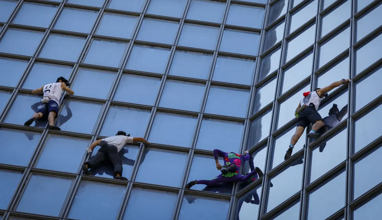 Pendaki Alain Robert (kedua kanan) atau Spiderman Prancis bersama Marcin Banot, Alexis Landot, dan Leo Urban memanjat Menara Total di La Defense, Paris, Prancis, 7 September 2021. Alain dengan tangan kosong memanjat menara setinggi 190 meter itu untuk menentang izin kesehatan. (THOMAS SAMSON/AFP)