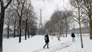 Aktivitas warga saat hujan salju di bawah Menara Eiffel di Paris, Prancis (7/2). Hujan salju yang sangat lebat membuat transportasi umum di paruh utara Prancis dan di Paris tidak dapat beroperasi. (AFP Photo / Thomas Samson)