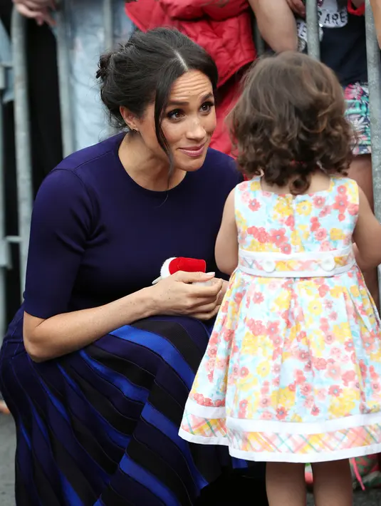 Duchess of Sussex, Meghan Markle menyapa anak kecil saat berjalan di Taman Pemerintah Rotorua, Selandia Baru, Rabu (31/10). Meghan dan Pangeran Harry sedang dalam tur tiga minggu di Australia, Selandia Baru, Tonga, dan Fiji. (Michael Bradley/Pool/AFP)