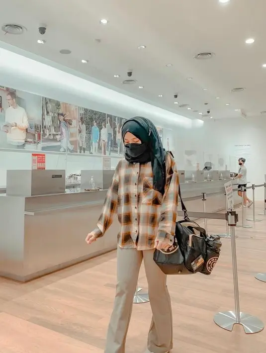 Simple tapi stylish, Putri Delina memadukan plaid shirt dengan loose pants warna cokelat. (Instagram/putridelinaa).