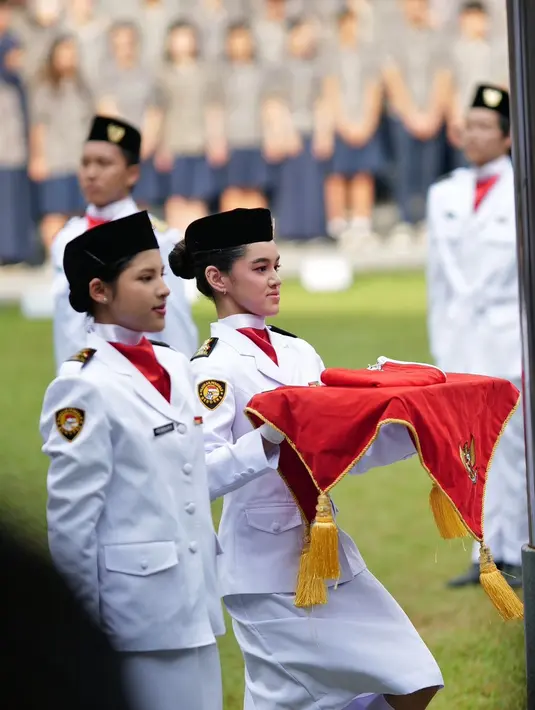 Sembari membawa baki bendera merah putih, Shaista terlihat melengkapi tampilannya dengan rambut yang disanggul rendah, peci hitam, slayer merah, dan pantofel hitam.  [@rio stokhorst].