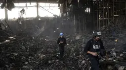 Wartawan berjalan di dalam gudang yang hancur untuk menyimpan makanan, setelah serangan dari Rusia dua belas hari lalu di Brovary, di pinggiran Kiev, Ukraina, Selasa, 29 Maret 2022. Invasi Rusia ke Ukraina yang dimulai pada 24 Feberuari 2022 masih berlangsung hingga hari ini. (AP Photo/Rodrigo Abd)