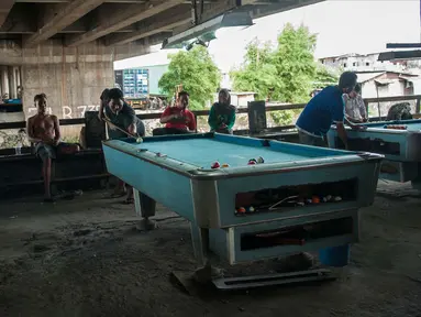 Sejumlah warga bermain biliar di kolong jembatan tol, Jakarta, Selasa (21/3). Tempat biliar sederhana ini menjadi tempat hiburan alternatif bagi masyarakat menengah kebawah di sekitar kolong tol. (Liputan6.com/Gempur M Surya)