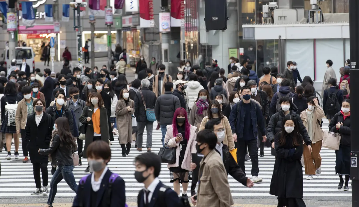 Orang-orang, yang mengenakan masker wajah, berjalan melintasi persimpangan di Tokyo (11/12/2020). Kurangnya tindakan pemerintah telah memicu kekhawatiran tentang kenaikan lebih lanjut selama musim liburan. (AP Photo / Hiro Komae)