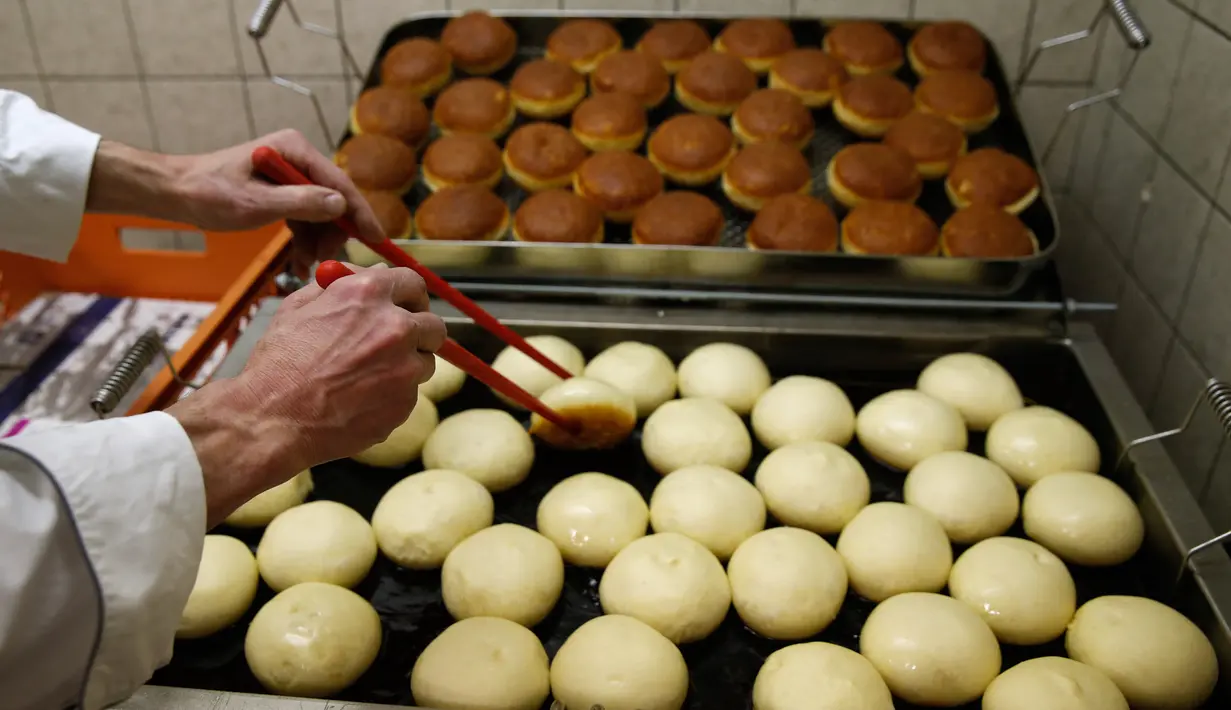 Seorang pekerja menyiapkan berliner (donat Jerman) yang akan dijual dengan jarum suntik penuh raspberry jelly di toko roti Kreyenbuhl di Muri, Swiss, 5 Februari 2021. Pembeli dapat menyuntikkan sendiri "vaksin" ke dalam donut dengan pilihan rasa raspberry atau Bailey-liqueur. (STEFAN WERMUTH/AFP)