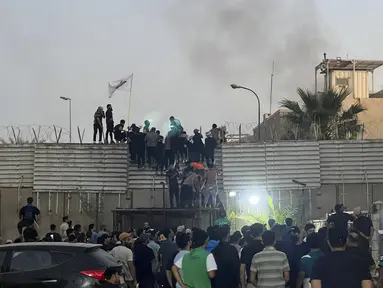 Para pengunjuk rasa memanjat tembok di Kedutaan Besar Swedia di Baghdad Kamis, 20 Juli 2023. (AP Photo/Ali Jabar)