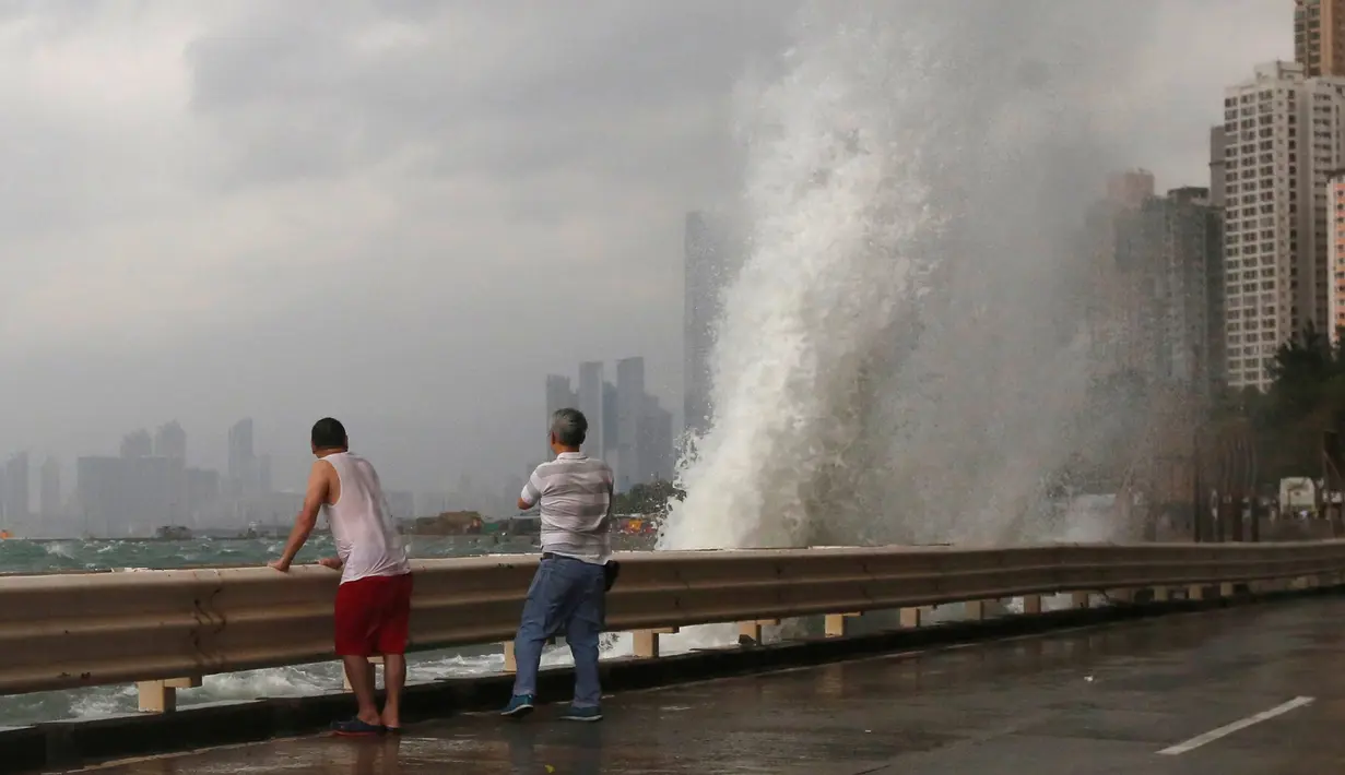 Dua warga menyaksikan ombak besar yang menerjang pesisir Hong Kong, Tiongkok, Jumat (21/10). Hongkong berada dalam kondisi waspada badai tingkat 8, level ketiga tertinggi dalam sistem peringatan bahaya topan. (REUTERS/Bobby Yip)