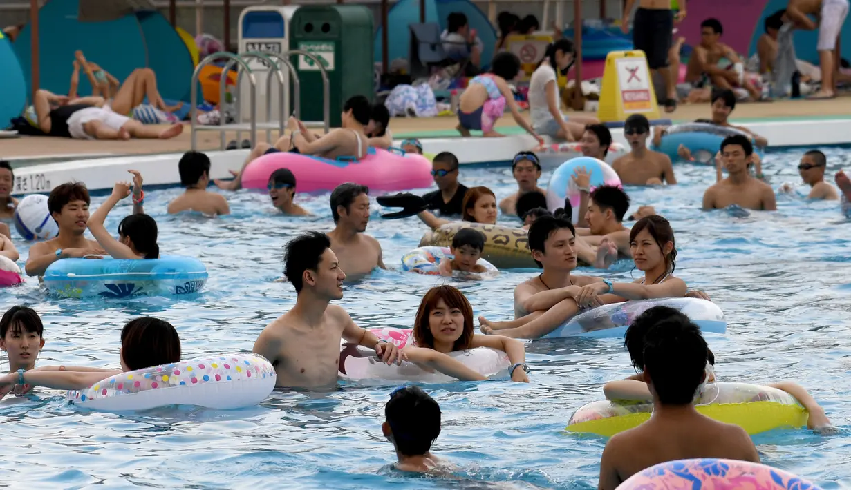 Pengunjung berada di kolam renang di sebuah taman hiburan di Tokyo, Jepang (19/7). Badan Meteorologi Jepang mengumumkan Jepang tengah, termasuk Tokyo, telah menyelesaikan musim hujan 'Tsuyu'.  (AFP Photo/Toshifumi Kitamura)
