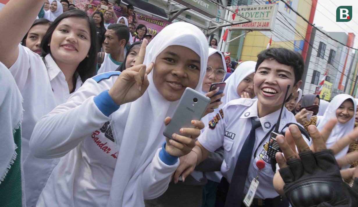 Warga turut menyambut kemeriahan pawai obor Asian Games XVIII di Lampung, Rabu (8/8/2018). Sebanyak 53 kota di Indonesia akan dilalui oleh obor Asian Games. (Bola.com/Reza Bachtiar)